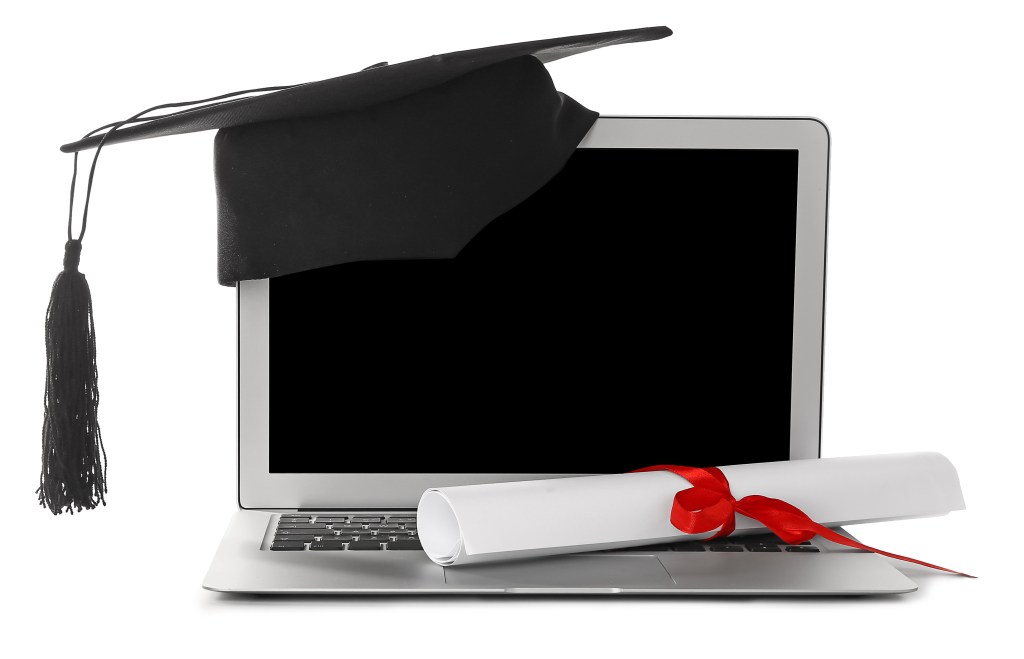 Graduation hat, laptop and diploma on white background