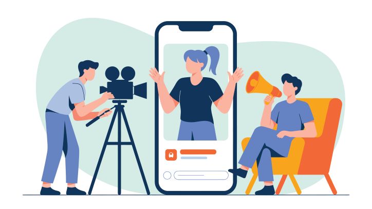 Three people: one with a camera recording the person in the centre. the third person holds a director's megaphone.